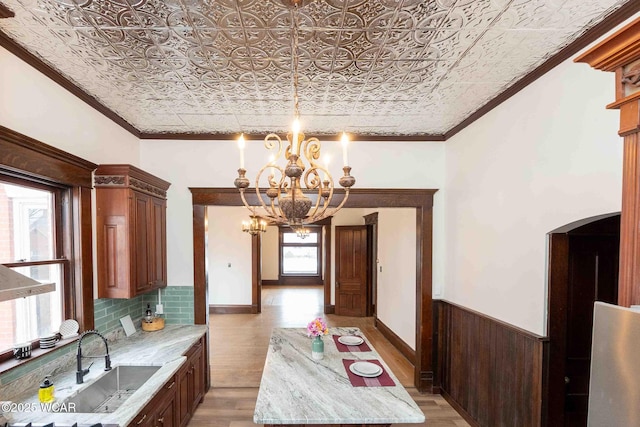 kitchen with sink, crown molding, light stone countertops, and light wood-type flooring