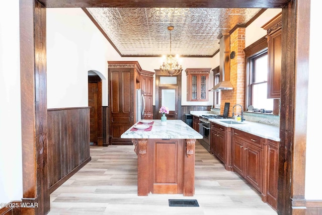 kitchen with sink, crown molding, appliances with stainless steel finishes, light hardwood / wood-style floors, and a kitchen island