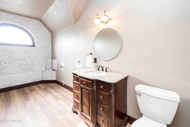 bathroom featuring hardwood / wood-style flooring, vaulted ceiling, vanity, and toilet