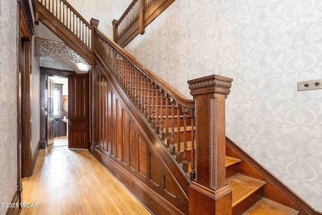 stairway with wood-type flooring and a high ceiling