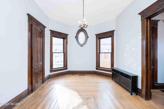 unfurnished room with a notable chandelier and light parquet flooring