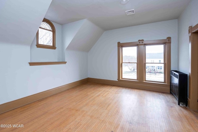 additional living space with vaulted ceiling and light hardwood / wood-style flooring