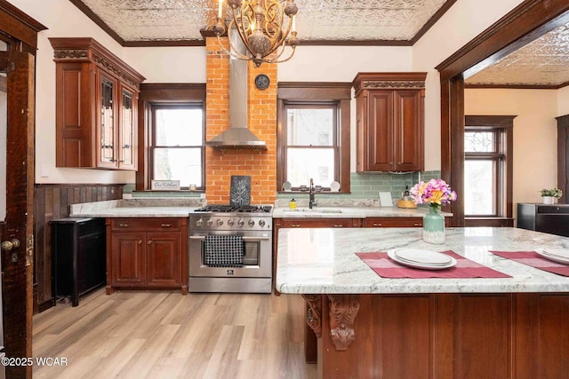 kitchen with sink, decorative light fixtures, light wood-type flooring, ornamental molding, and stainless steel stove