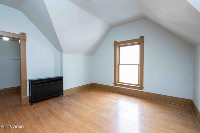 additional living space with light hardwood / wood-style flooring and vaulted ceiling