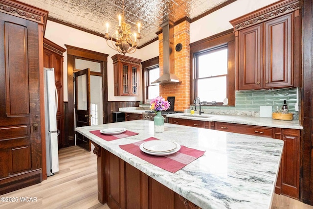 kitchen featuring sink, brick ceiling, hanging light fixtures, ventilation hood, and white fridge