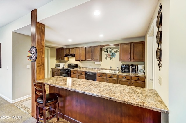 kitchen featuring under cabinet range hood, recessed lighting, a sink, black appliances, and a kitchen bar