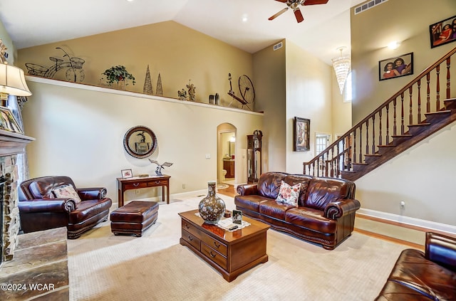 carpeted living room featuring high vaulted ceiling, arched walkways, a fireplace with raised hearth, and stairs