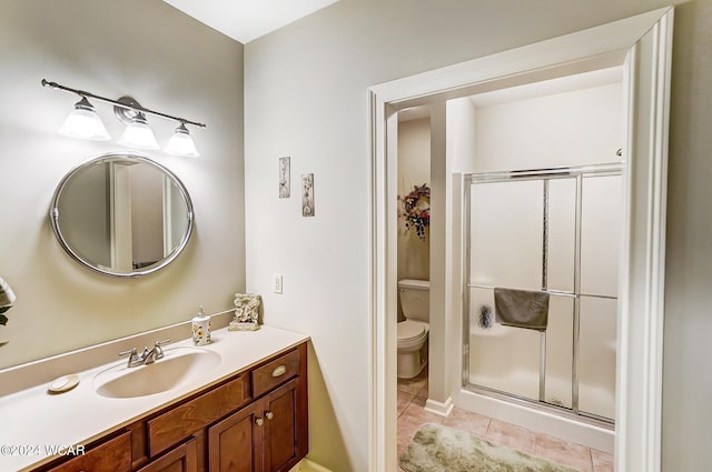 bathroom with a stall shower, vanity, toilet, and tile patterned floors