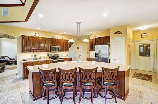 kitchen featuring an island with sink, appliances with stainless steel finishes, light countertops, a sink, and recessed lighting