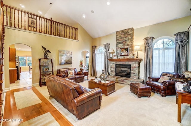 living room featuring high vaulted ceiling, arched walkways, and a fireplace