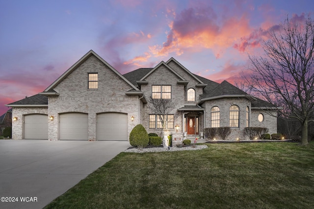 french country style house with driveway, brick siding, a front yard, and a shingled roof