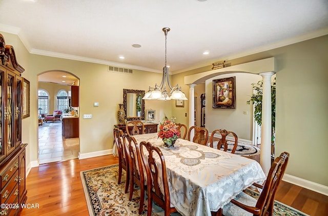 dining room with arched walkways, visible vents, and light wood finished floors