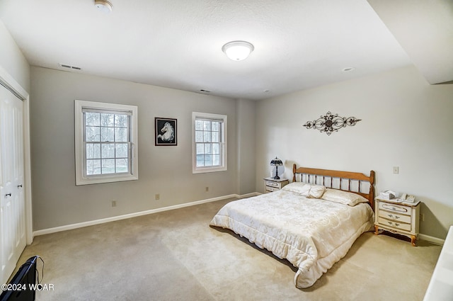 carpeted bedroom with visible vents, baseboards, and a closet