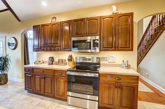 kitchen with arched walkways, stainless steel appliances, light countertops, and baseboards