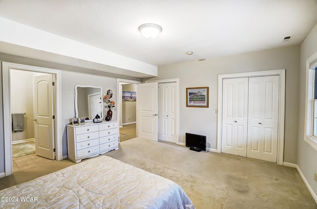 bedroom featuring visible vents, baseboards, connected bathroom, light colored carpet, and two closets