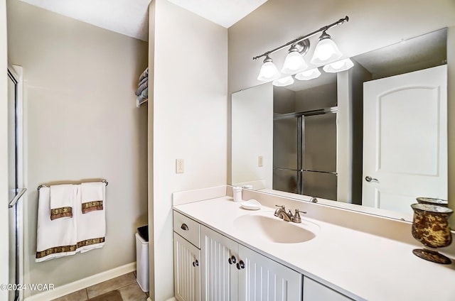 bathroom featuring baseboards, vanity, a shower with shower door, and tile patterned floors