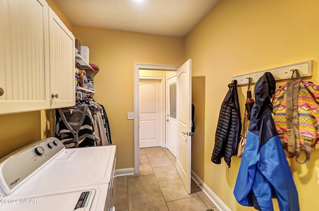 clothes washing area with light tile patterned floors, cabinet space, baseboards, and separate washer and dryer