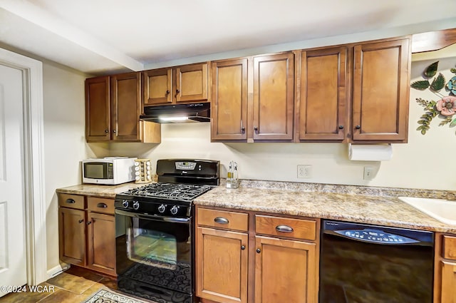 kitchen featuring brown cabinets, under cabinet range hood, and black appliances