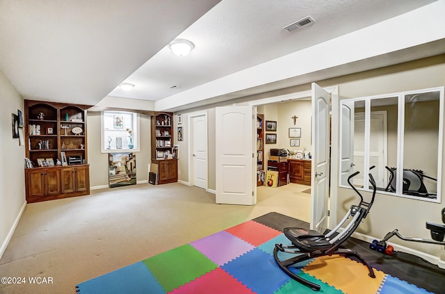 workout area featuring visible vents, light carpet, and baseboards