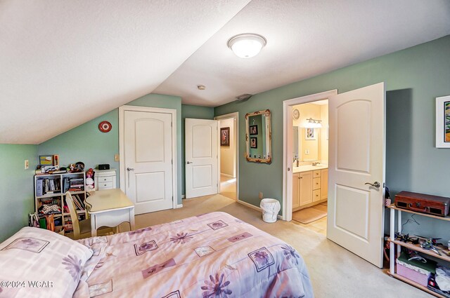 bedroom with lofted ceiling, ensuite bathroom, and light colored carpet