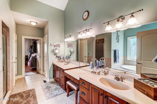 bathroom with tile patterned floors, a walk in closet, vanity, a shower stall, and a bath