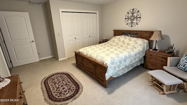 bedroom with a closet, light carpet, and baseboards