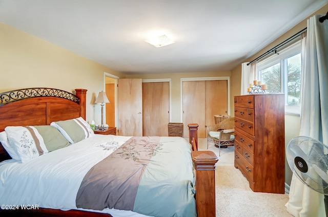 bedroom featuring two closets and light colored carpet