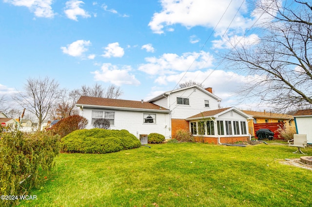 rear view of property featuring a yard and a sunroom