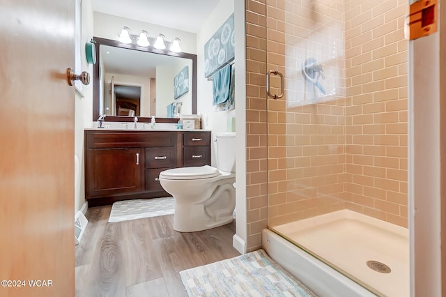 bathroom featuring vanity, wood-type flooring, a shower with door, and toilet