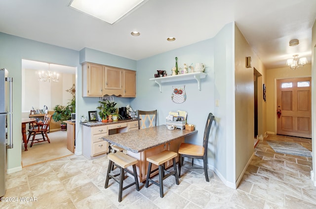 kitchen featuring light brown cabinetry, a notable chandelier, and a kitchen bar