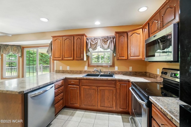 411 Ethan Cir, Bluffton, OH 45817 - kitchen with appliances with stainless steel finishes, a sink, a peninsula, brown cabinetry, and healthy amount of natural light