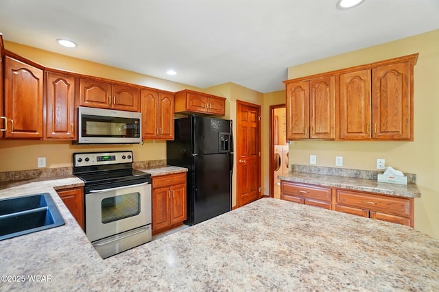 411 Ethan Cir, Bluffton, OH 45817 - kitchen featuring stainless steel appliances, recessed lighting, a sink, brown cabinets, and washing machine and dryer