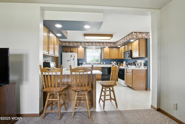 19318 Middle Point Rd, Van Wert, OH 45891 - kitchen featuring black appliances, a peninsula, a kitchen bar, brown cabinets, and light countertops