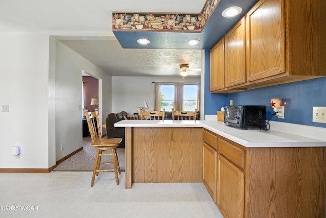 19318 Middle Point Rd, Van Wert, OH 45891 - kitchen with a peninsula, a kitchen breakfast bar, light countertops, brown cabinets, and open floor plan