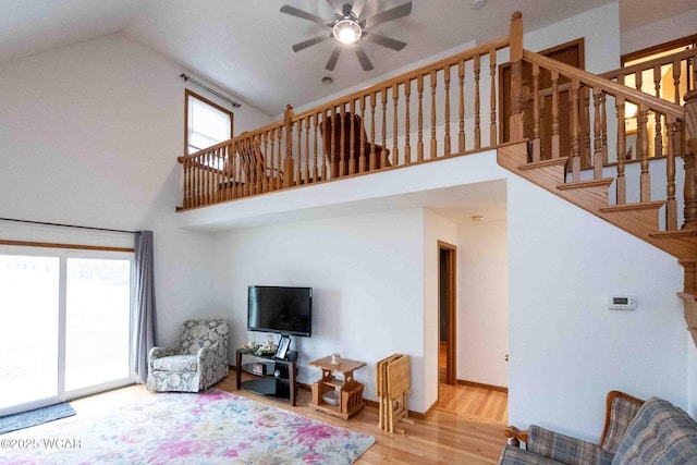 living room with hardwood / wood-style floors, ceiling fan, and a high ceiling