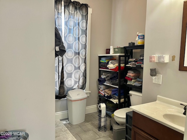 bathroom featuring baseboards, vanity, and toilet