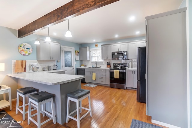 kitchen featuring gray cabinets, a kitchen breakfast bar, hanging light fixtures, kitchen peninsula, and stainless steel appliances