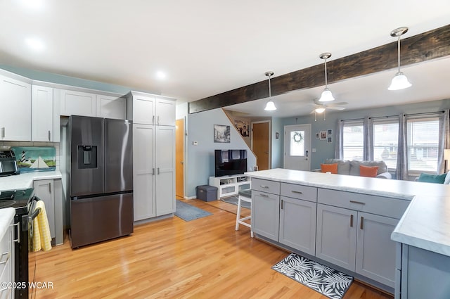 kitchen featuring stainless steel fridge with ice dispenser, decorative light fixtures, a breakfast bar area, gray cabinetry, and black range with electric cooktop