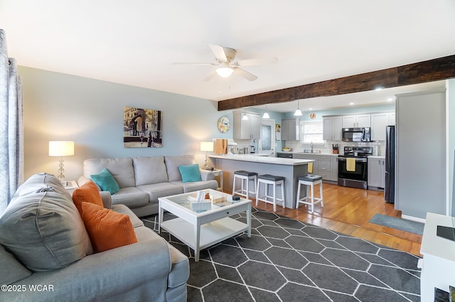 living room featuring beamed ceiling, ceiling fan, sink, and dark hardwood / wood-style flooring