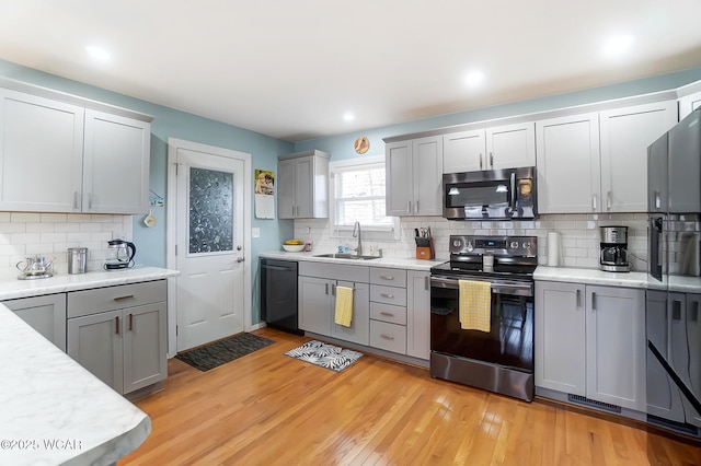 kitchen featuring appliances with stainless steel finishes, sink, gray cabinetry, and light hardwood / wood-style flooring