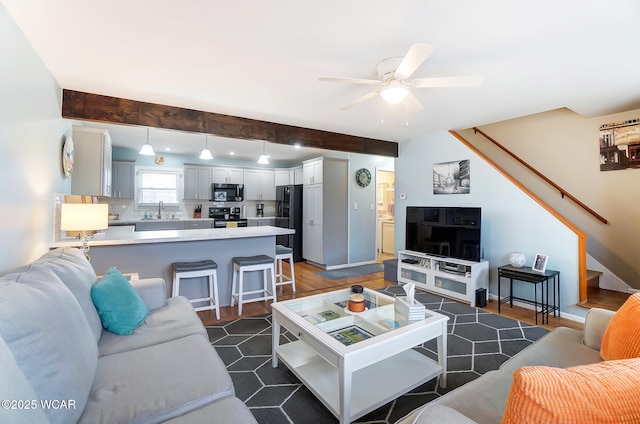 living room featuring sink, beam ceiling, and ceiling fan