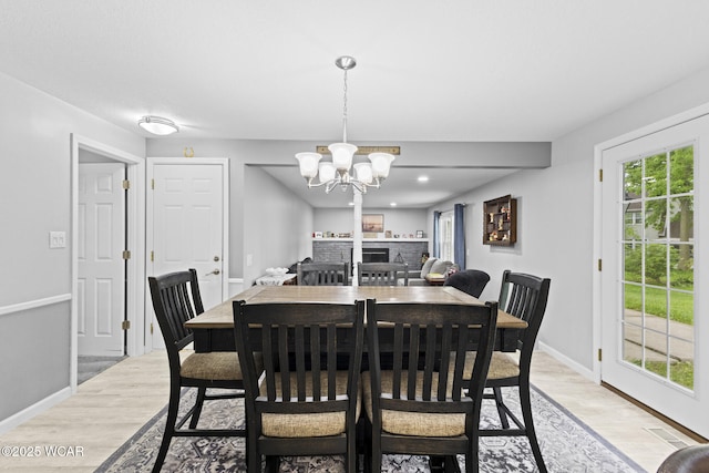 120 Barnsbury Dr, Lima, OH 45804 - dining space featuring light wood-style floors, a chandelier, baseboards, and a brick fireplace