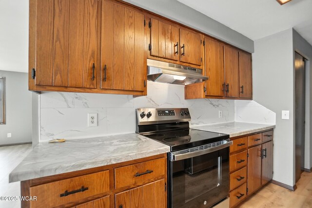 591 Monticello Ave Unit A, Lima, OH 45804 - kitchen with electric range, under cabinet range hood, light wood-type flooring, brown cabinets, and decorative backsplash