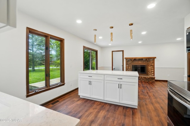 1257 Timberlane Dr, Lima, OH 45805 - kitchen featuring dark wood finished floors, recessed lighting, white cabinetry, hanging light fixtures, and a brick fireplace