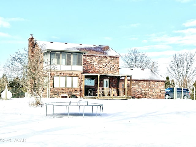 snow covered house with a trampoline and covered porch