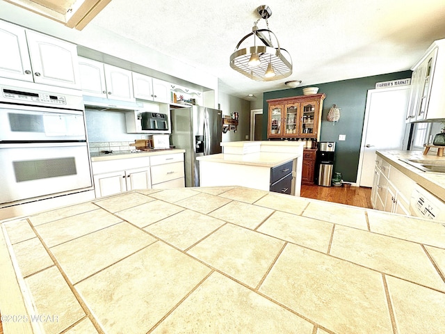 kitchen with pendant lighting, white cabinetry, and white appliances