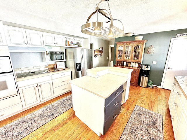 kitchen with a center island, stainless steel refrigerator with ice dispenser, light hardwood / wood-style floors, white cabinets, and black cooktop