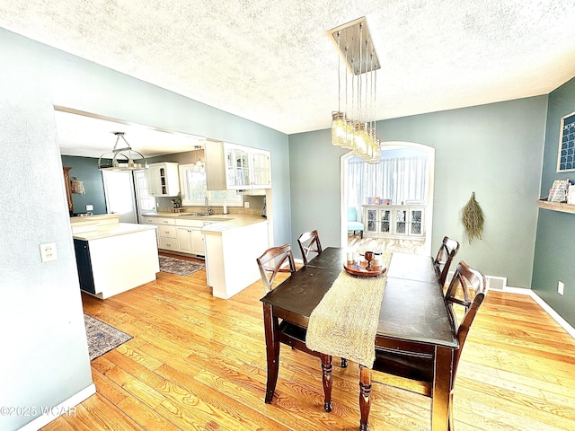 dining room with sink, light hardwood / wood-style flooring, and a textured ceiling