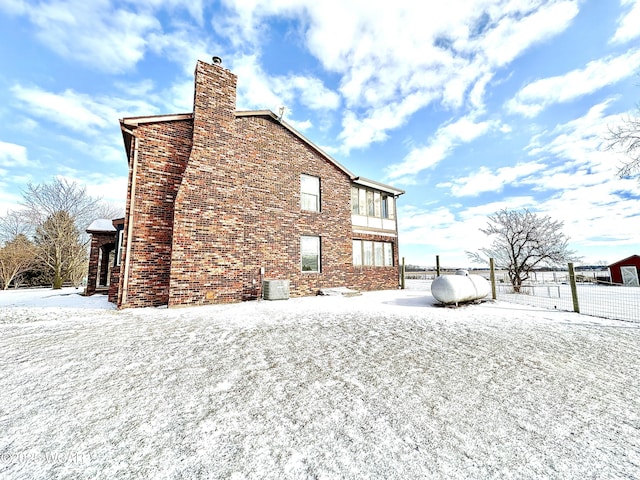 snow covered house featuring central AC unit