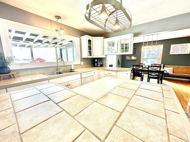 kitchen with sink, pendant lighting, white cabinets, and white dishwasher